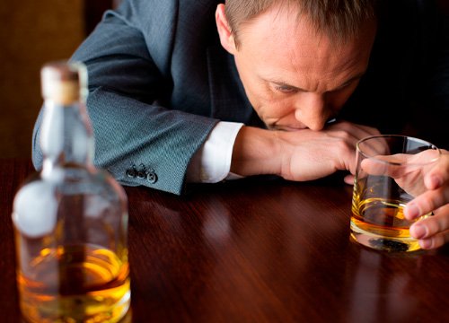 Мужчина выпивает за столом Мужчина сидит за столом